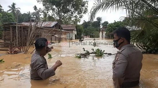 Petugas memantau rumah yang terendam ditengah banjir.