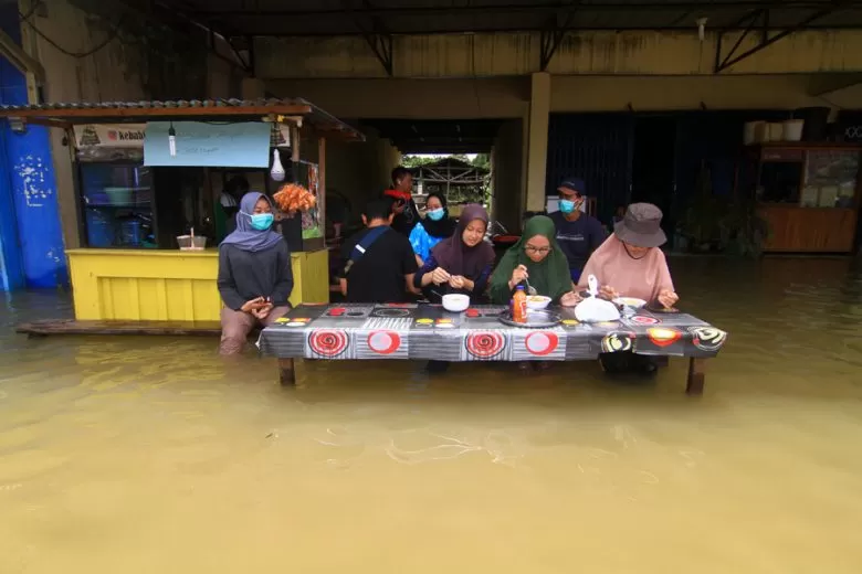 Sejumlah warga menyantap makanan di sebuah warung yang terendam banjir di Putussibau, Kabupaten Kapuas Hulu, Kalimantan Barat, Selasa (15/9/2020). Banjir setinggi 1-5 meter yang melanda Putussibau sejak Minggu (13/9/2020) hingga Selasa (15/9/2020) melumpuhkan aktivitas masyarakat di kota tersebut. ANTARA FOTO/Jessica Helena Wuysang/pras.