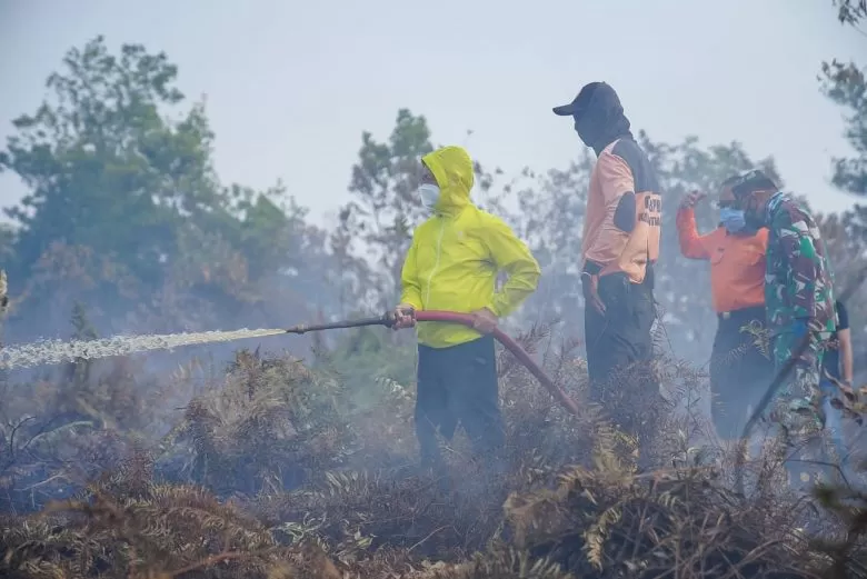 PADAMKAN API: Wali Kota Pontianak Edi Rusdi Kamtono ikut memadamkan lahan yang terbakar di Kecamatan Pontianak Selatan. Pemkot menyegel lahan yang disengaja dibakar. MIRZA/PONTIANAK POST