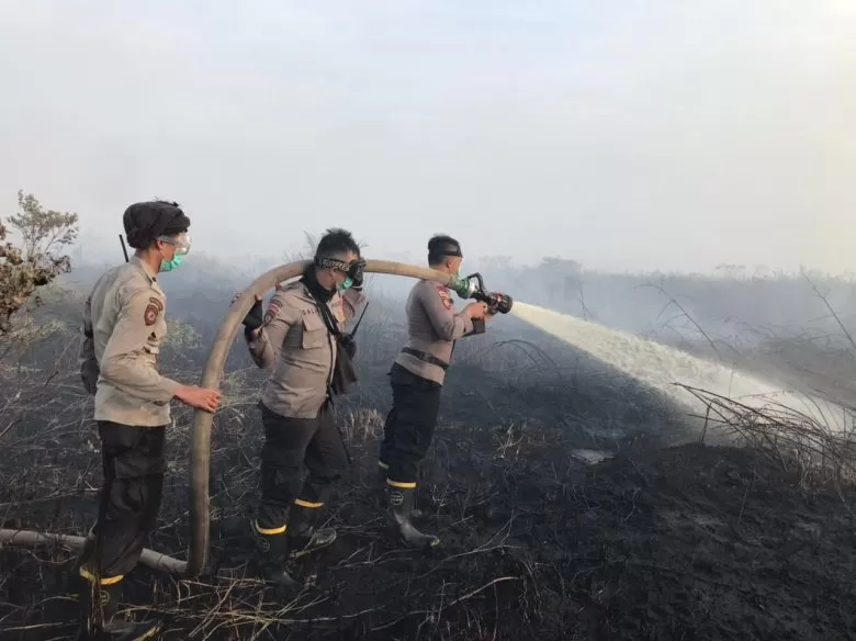 KARHUTLA: Tiga personel kepolisian berusaha memadam kebakaran lahan, kemarin. sebanyak delapan orang telah ditetapkan sebagai tersangka kasus kebakaran hutan dan lahan di Kalimantan Barat. ISTIMEWA