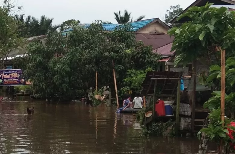 BANJIR: Air menggenangi sejumlah rumah dan jalan di Desa Lumbang Kecamatan Sambas. Terlihat anak-anak bermain ar dengan menggunakan ban mobil.OZY/PONTIANAKPOST