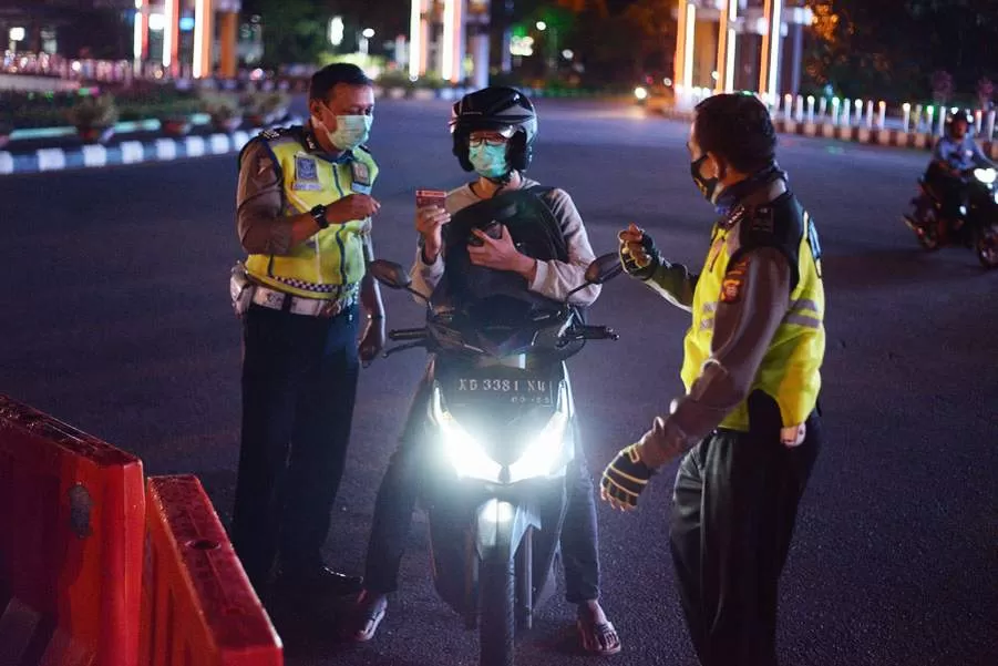 MEMERIKSA: Petugas kepolisian tengah memeriksa kelengkapan surat pengendara yang akan melewati penyekatan jalan di kawasan bundaran Digulis Universitas Tanjungpura, Pontianak, kemarin. ARIEF NUGROHO/PONTIANAK POST