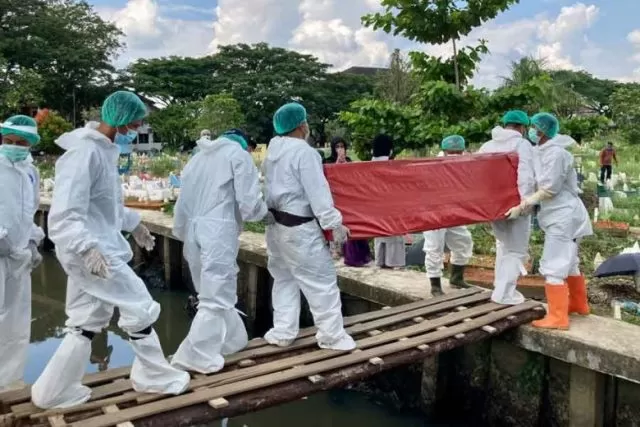 TITIAN; Petugas tenaga kesehatan (nakes) menggunakan APD melintasi titian barau saat akan melakukan pemakaman jenazah di TPU Sungai Bangkong. (ARIEF NUGROHO/PONTIANAK POST)