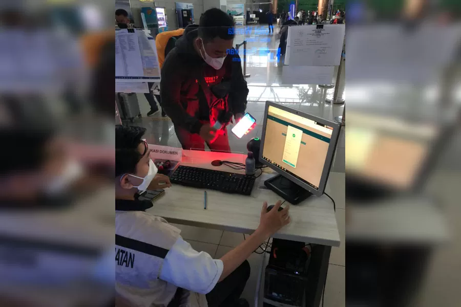 Petugas Bandara Internasional Supadio sedang melakukan pemeriksaan dokumen penumpang dengan scan barcode yang terafiliasi dengan aplikasi peduli lindungi untuk memverifikasi persyaratan dokumen penerbangan. IST