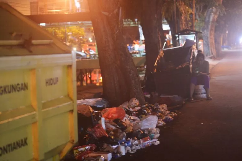 MENIKMATI MAKANAN RINGAN: Seorang ibu yang sehari-hari bergelut dengan sampah perkotaan, menikmati makanan ringan yang dibawanya tidak jauh dari tempat pembuangan sampah di Jalan H. Rais A. Rahman. MEIDY KHADAFI/PONTIANAK POST