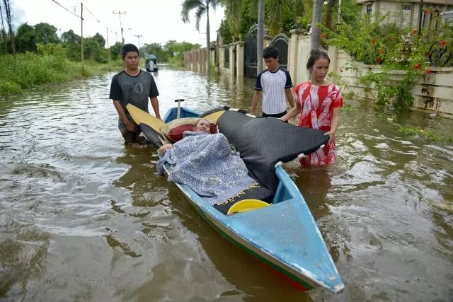 ANTAR WARGA SAKIT: Warga mengevakuasi seorang warga yang menderita sakit menggunakan perahu sampan mengarungi banjir di jalan Dharma Putra, Kelurahan Ladang, Kecamatan Sintang. (ARIEF NUGROHO/PONTIANAK POST