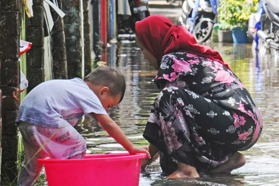PASANG LAUT: Seorang anak bermain air ditemani ibunya yang mencuci keset kaki digenangan air, akibat pasang air laut di depan rumahnya di Jalan Adi Sucipto, Kecamatan Pontianak Tenggara, Kamis (9/12). HARYADI/PONTIANAKPOST