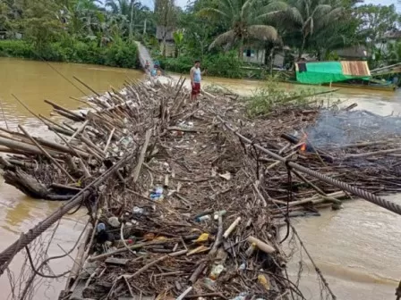 Material batang pohon dan sampah menyangkut di jembatan gantung Dusun Sejaya Desa Kuala Behe Kecamatan Kuala Behe, Jumat (10/3). (ISTIMEWA)