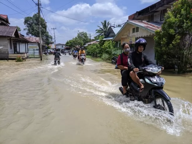 Warga melintasi Jalan Pangeran Cinata Desa Hilir Tengah yang terendam banjir, Selasa (14/3). (MIFTAHUL KHAIR/PONTIANAK POST)