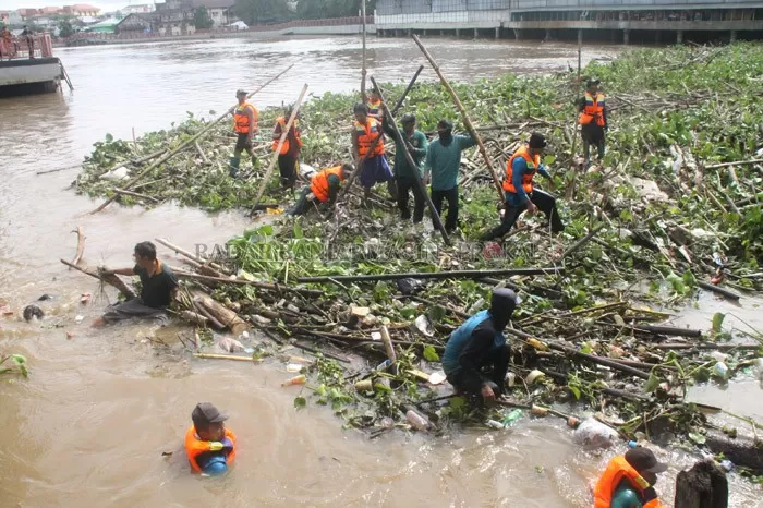 KERJA EKSTRA: Pasukan turbo alias petugas kebersihan PUPR berjibaku membersihkan sampah dan gulma di Sungai Martapura. Mereka dituntut siaga selama musim hujan. | FOTO: NOORHIDAYAT/RADAR BANJARMASIN