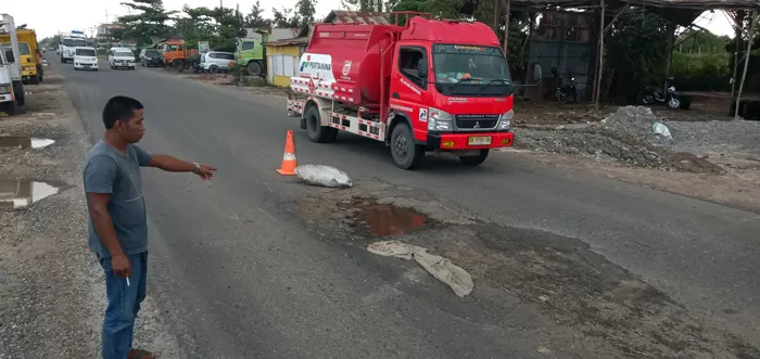 Syaifullah menunjukkan lubang dan jalan yang rusak di Jalan Gubernur Subarjo RT 13 Banjarmasin Selatan.