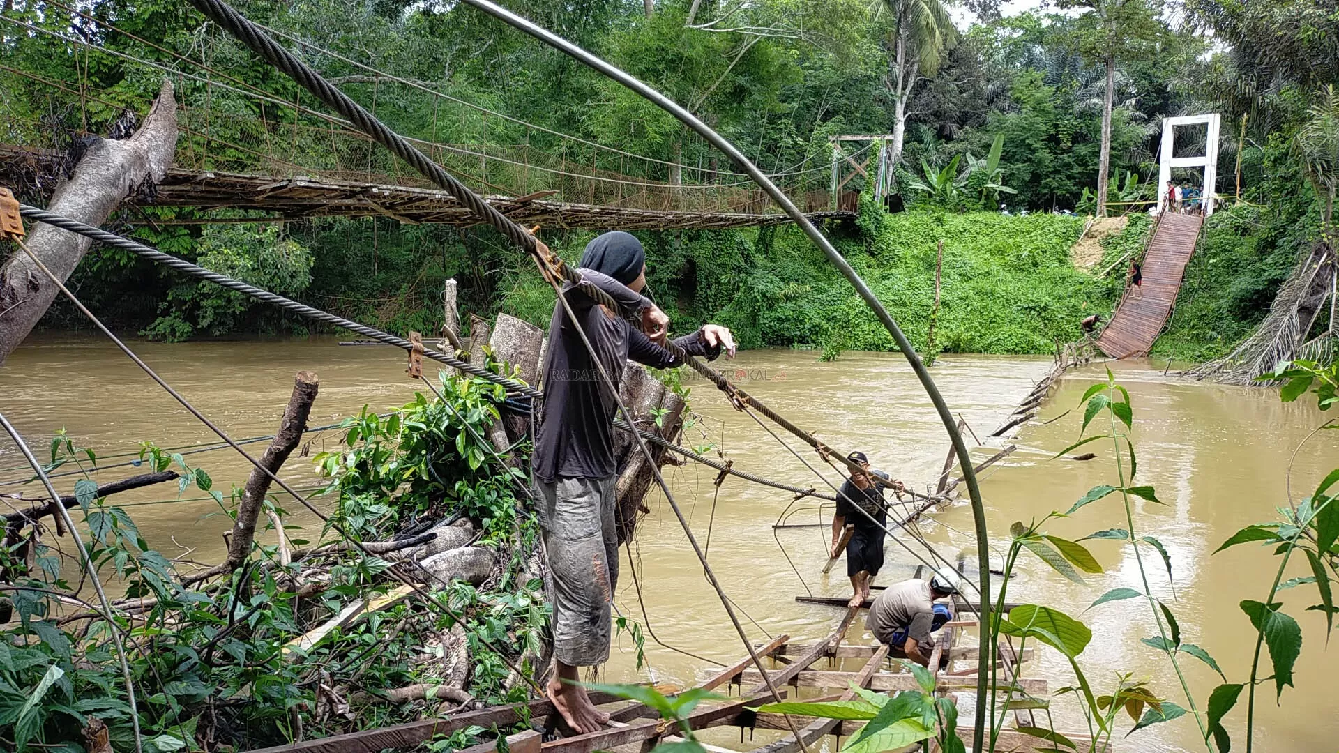 AMBRUK : Kondisi jembatan gantung di Desa Babayau yang ambruk. Tampak beberapa warga mengambil material yang masih bisa diselamatkan. | FOTO: WAHYUDI/RADAR BANJARMASIN