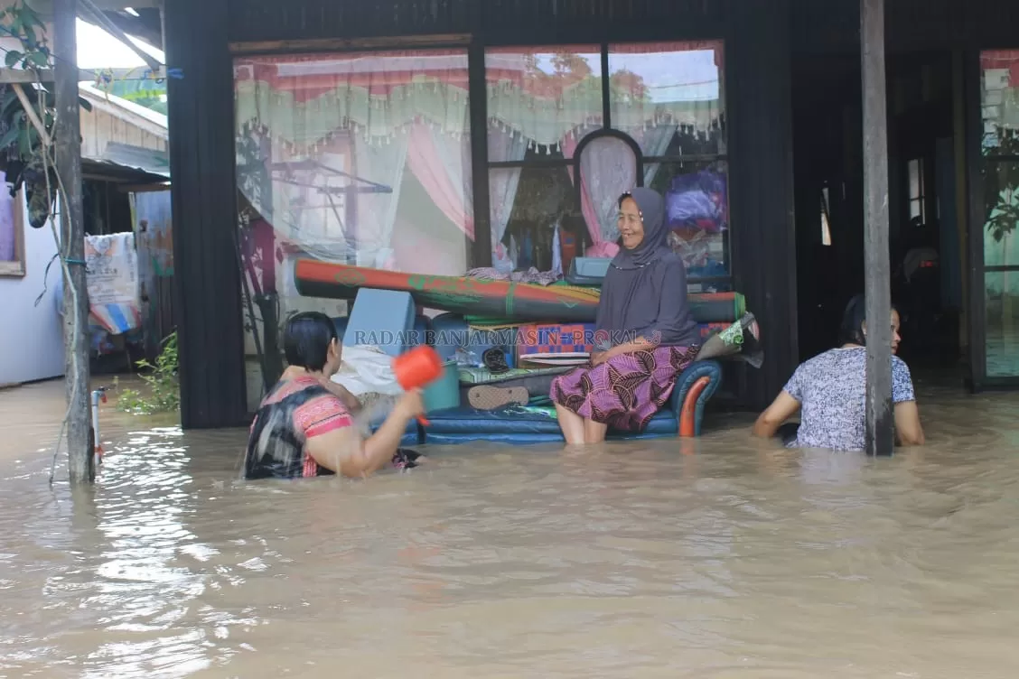 MANDI DI TERAS: Sejumlah warga memilih mandi di teras depan rumah mereka yang terendam banjir.  |  Foto: Fadly /Radar Banjarmasin