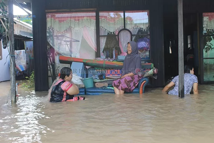 MANDI DEPAN RUMAH: Warga Kelurahan Kupang, Tapin bercengkerama sambil mandi saat banjir Tapin, baru-baru tadi. | FOTO: RASIDI FADLY/RADAR BANJARMASIN