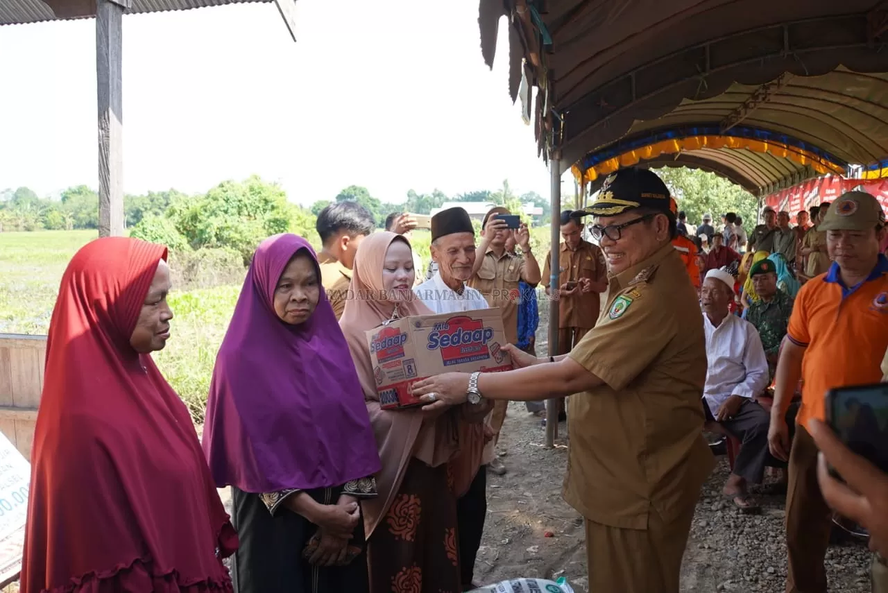PEDULI : Bupati Balangan Ansharuddin (kanan) menyerahkan bantuan sembako kepada warga Desa Pimping. | FOTO: WAHYUDI/RADAR BANJARMASIN.