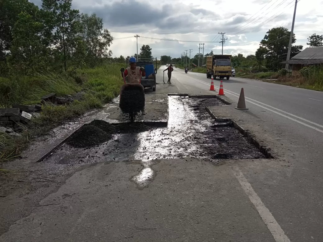 MARTAPURA LAMA: Para pekerja saat memperbaiki Jalan Martapura Lama yang merupakan kewenangan Dinas PUPR Kalsel. Perbaikan jalan dilakukan untuk kelancaran lalu lintas jemaah Haul ke-15 Guru Sekumpul. | FOTO: DINAS PUPR KALSEL