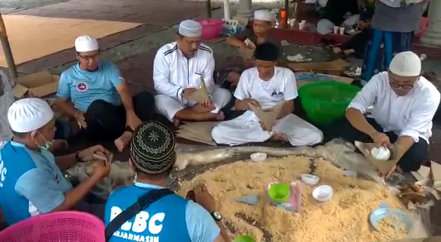 Relawan tengah mempersiapkan nasi samin yang dibungkus dengan kertas minyak.
