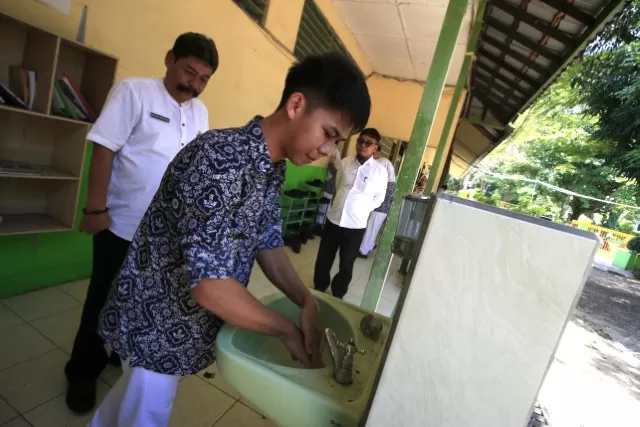 CUCI TANGAN: Salah seorang siswa SMAN 2 Banjarbaru menyuci kedua tangannya sebelum memasuki ruangan kelas di sebuah wastafel. Hal ini terkait maraknya isu penyebaran Covid-19 di Indonesia. | Foto: Muhammad Rifani/Radar Banjarmasin