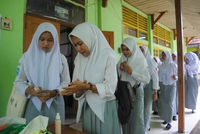 Siswa SMKN 1 Banjarbaru mengantre pembersih tangan buatan guru mereka sendiri sebelum memasuki ruangan ujian. | Foto: SUTRISNO/RADAR BANJARMASIN