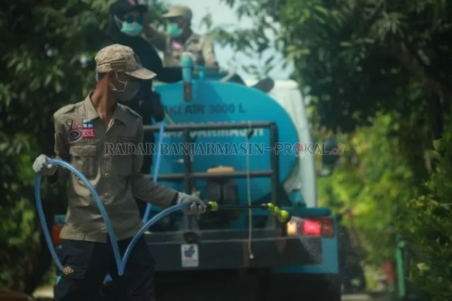 DISINFEKSI: Petugas Badan Penanggulangan Bencana Daerah (BPBD) menyemprotkan cairan disinfektan di kawasan Banjarmasin Utara. | FOTO: FAHRIADI NUR/RADAR BANJARMASIN