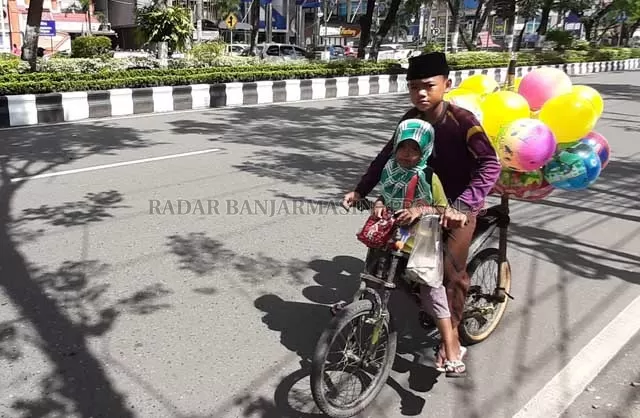HARUS DIBANTU: Bocah berdagang balon melintasi Jalan Lambung Mangkurat, kemarin (13/4). Warga kecil inilah yang harus ditolong. | FOTO: WAHYU RAMADHAN/RADAR BANJARMASIN