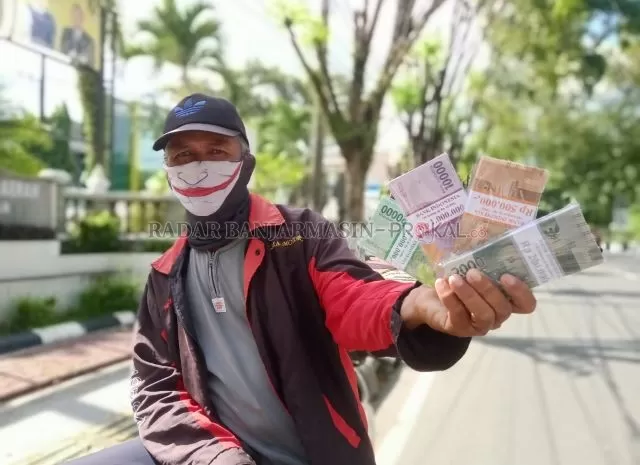 TUKAR UANG: Pedagang jasa tukar uang pecahan kecil di Jalan Lambung Mangkurat, Ijun, ketika sedang menunggu pembeli, kemarin (8/5) siang. | FOTO: ENDANG SYARIFUDDIN/RADAR BANJARMASIN