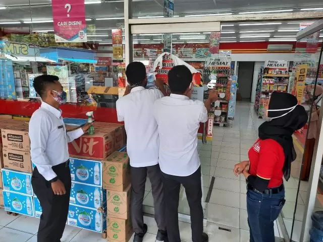 DILEPAS: Petugas BP2RD Kota Banjarbaru melepas stiker pemberitahuan tunggakan pajak di gerai Alfamart di Banjarbaru. | FOTO: BP2RD Banjarbaru for Radar Banjarmasin