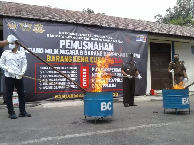 DIBAKAR: Pemusnahan satu juta batang rokok ilegal di depan kantor Bea dan Cukai di Banjarmasin Barat. Pada waktu bersamaan di TPA Banjarbaru dimusnahkan ratusan miras. | FOTO: POLSEK BANJARMASIN TIMUR FOR RADAR BANJARMASIN