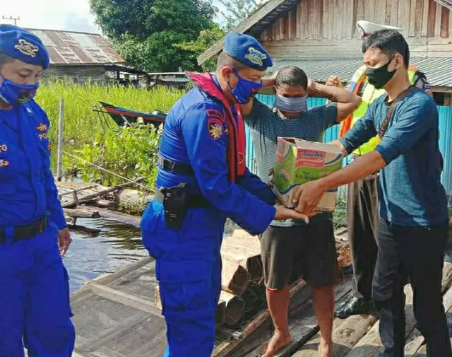 PEDULI: Kasat Polair Polres HSU, Iptu Ashari saat menyerahkan bantuan sembako pada warga di tepi Sungai Barito Kecamatan Paminggir.