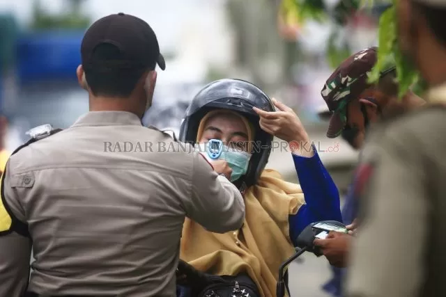 DIPERIKSA: Salah seorang pengendara yang mau melintas menuju Kota Banjarbaru diperiksa KTP serta suhu badannya oleh petugas gabungan di Posko 2 PSBB Gabungan di depan Q Mall Banjarbaru pada Senin (18/6) siang. | Foto: Muhammad Rifani/Radar Banjarmasin