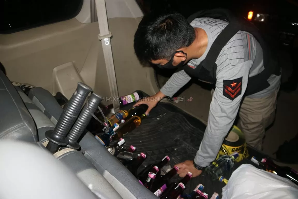 BARANG BUKTI; Kapolsek Tapin Utara, Ipda Subroto Rindang Ari Setyawan, menyusun barang bukti minuman keras yang diamankan dimobilnya. | Foto: Rasidi Fadli/Radar Banjarmasin