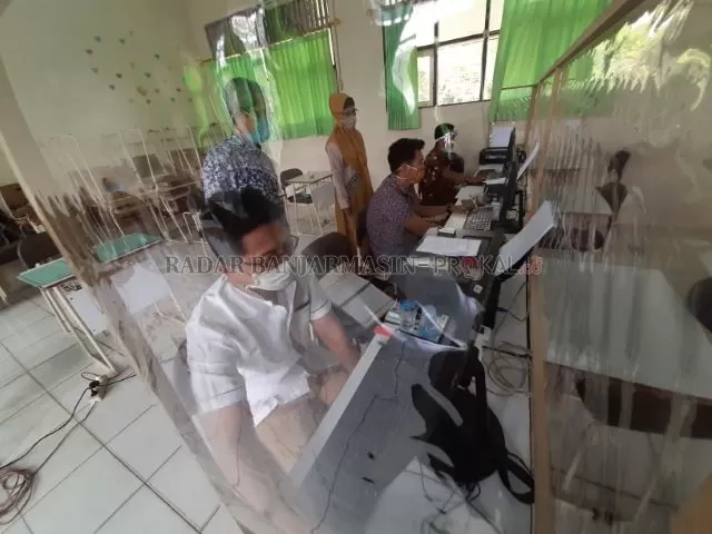 PROTOKOL KESEHATAN: Para petugas di salah satu SMPN di Banjarmasin menginput data pelaksanaan PPDB secara daring. | FOTO: WAHYU RAMADHAN/RADAR BANJARMASIN