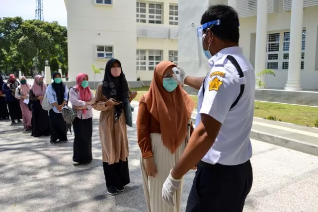 UKUR SUHU TUBUH DULU: Para pelajar mengikuti tes masuk perguruan tinggi di sebuah universitas di Aceh, kemarin. Di tengah pandemi, beberapa daerah mulai kembali menyelenggarakan pendidikan.  | FOTO: CHAIDEER MAHYUDIN/AFP