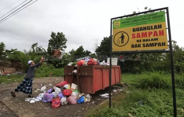 BERDAMPAK: Salah seorang warga melempar bungkusan sampah miliknya ke sebuah bak sampah di Jalan Trikora Banjarbaru. Selama pandemi, DLH Banjarbaru mencatat produksi sampah di Kota Banjarbaru menyusut hingga 20 ton perharinya. | FOTO: MUHAMMAD RIFANI/RADAR BANJARMASIN