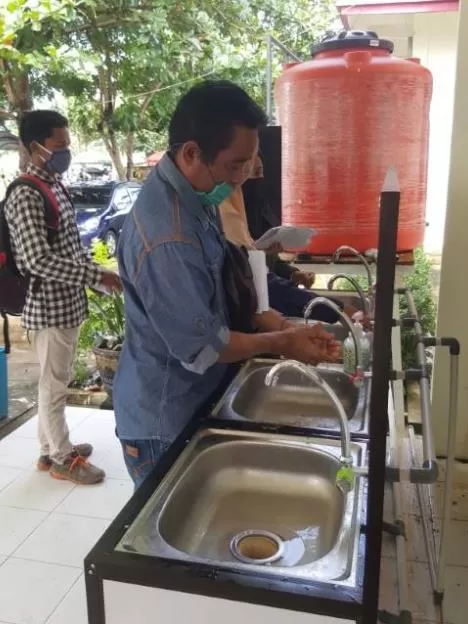 CUCI TANGAN: Warga yang ingin mengurus administrasi kependudukan di Disdukcapil wajib mencuci tangan memakai sabun. (Foto Karyono/Radar Banjarmasin).