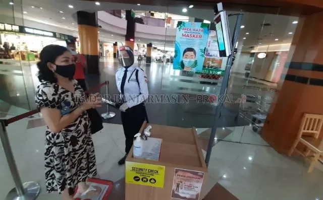 DICEK DULU: Seorang pengunjung mall di Banjarmasin diperiksa sebelum masuk. Banjarmasin menetapkan zona hijau di beberapa kecamatan meski secara keseluruhan kasus belum menurun. | FOTO: WAHYU RAMADHAN/RADAR BANJARMASIN