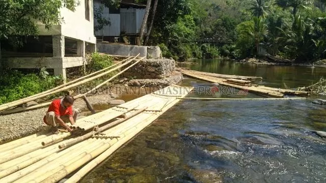 MULAI LAGI: Joki bamboo rafting di Loksado memeriksa rakit yang digunakan untuk menyusuri sungai Amandit. | FOTO: SALAHUDIN/RADAR BANJARMASIN