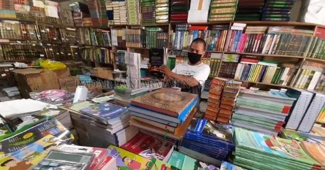 JENDELA DUNIA: Jarkani merapikan buku di toko miliknya di Jalan Hasanuddin HM, kemarin (20/8) siang. Sentra penjualan buku teks pelajaran tak luput dari dampak pandemi. | Foto: Wahyu Ramadhan/Radar Banjarmasin