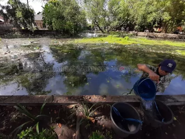 TIMBA: Alan menimba air dari sungai di pinggir Jalan Sutoyo S. Sekalipun sungai itu kotor sekali. | FOTO: WAHYU RAMADHAN/RADAR BANJARMASIN