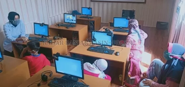 TEROBOSAN: Anak-anak belajar daring di Poskotis ditemani polwan. Fasilitas di samping Jembatan Antasari itu disediakan selama pandemi. | FOTO: MAULANA/RADAR BANJARMASIN