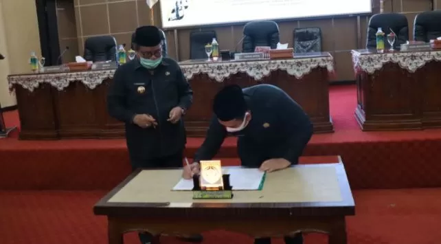 PENANDATANGANAN: Ketua DPRS Balangan Ahsani Fauzan (kanan) bersama Bupati Balangan Ansharuddin, menandatangani berita acara paripurna. | FOTO: WAHYUDI/RADAR BANJARMASIN.