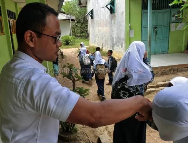 MENGABDI: Seorang guru honorer di pelosok Pulau Laut, Kotabaru melepas siswa seusai sekolah. | DOK/RADAR BANJARMASIN