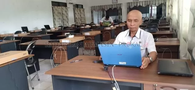 SIAPKAN: Kasubid Formasi dan Mutasi BKD Diklat Kabupaten HSS, Zulkifli Mahmud memeriksa laptop untuk digunakan tes SKB 13-17 September mendatang. | FOTO: SALAHUDIN/RADAR BANJARMASIN