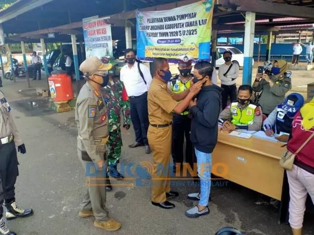 MASKER: Bupati Tala Sukamta memasangkan masker dengan benar kepada warga.