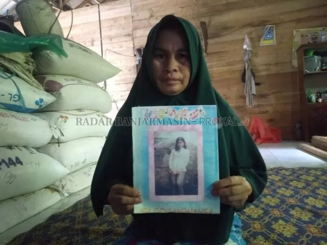 FOTO: Sainah (47) saat menunjukkan kenangan foto Latifah di masa remaja. | FOTO: JAMALUDDIN/RADAR BANJARMASIN
