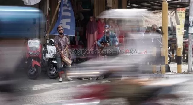PERHATIKAN MEREKA: Arul dan Udin mengamen di perempatan Jalan Perintis Kemerdekaan, Pasar Lama, kemarin (4/10). | FOTO: WAHYU RAMADHAN/RADAR BANJARMASIN