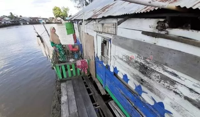 MANUSIA SUNGAI: Abasiah, berdiri di teras rumah lantingnya, kemarin (11/10). Dia sudah tinggal mengapung di atas Sungai Martapura selama 36 tahun. | FOTO: WAHYU RAMADHAN/RADAR BANJARMASIN