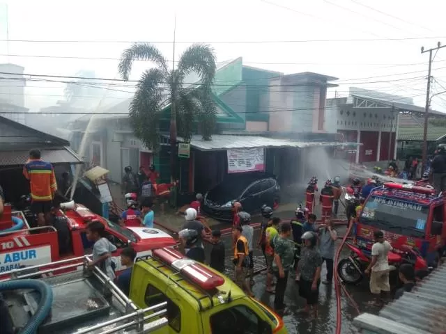 PEMADAMAN: Damkar HST dan warga sekitar pun berusaha memadamkan api yang membakar sebuah toko dan rumah di Jalan Sarigading, Kecamatan Barabai, Hulu Sungai Tengah, Senin (12/10) sore.