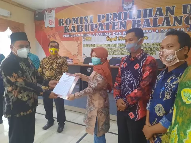 PENYERAHAN: Ketua KPU Balangan Saripani (kiri) menyerahkan berita acara rapat pleno kepada salah satu perwakilan tim paslon. | FOTO: BAYU FOR RADAR BANJARMASIN.