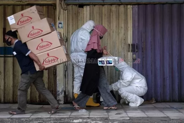 SIAP TES: Seorang wanita melewati para petugas yang bersiap untuk Rapid test di Pasar Sentra Antasari Banjarmasin saat PSBB laluPembatasan karena pandemi ditengarai mendongkrak kasus kekerasan perempuan dan anak. | FOTO: DOK/RADAR BANJARMASIN